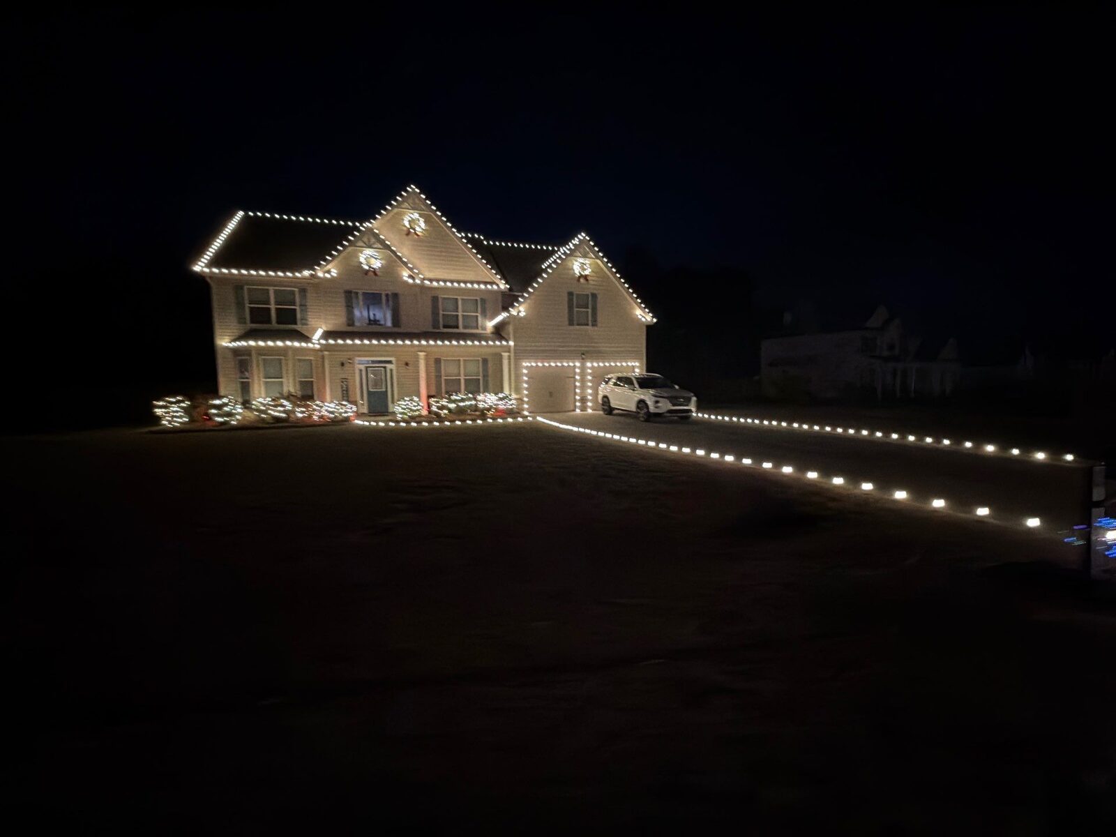 Home with warm white C9 Christmas roofline lights, wrapped bushes and pathway lighting