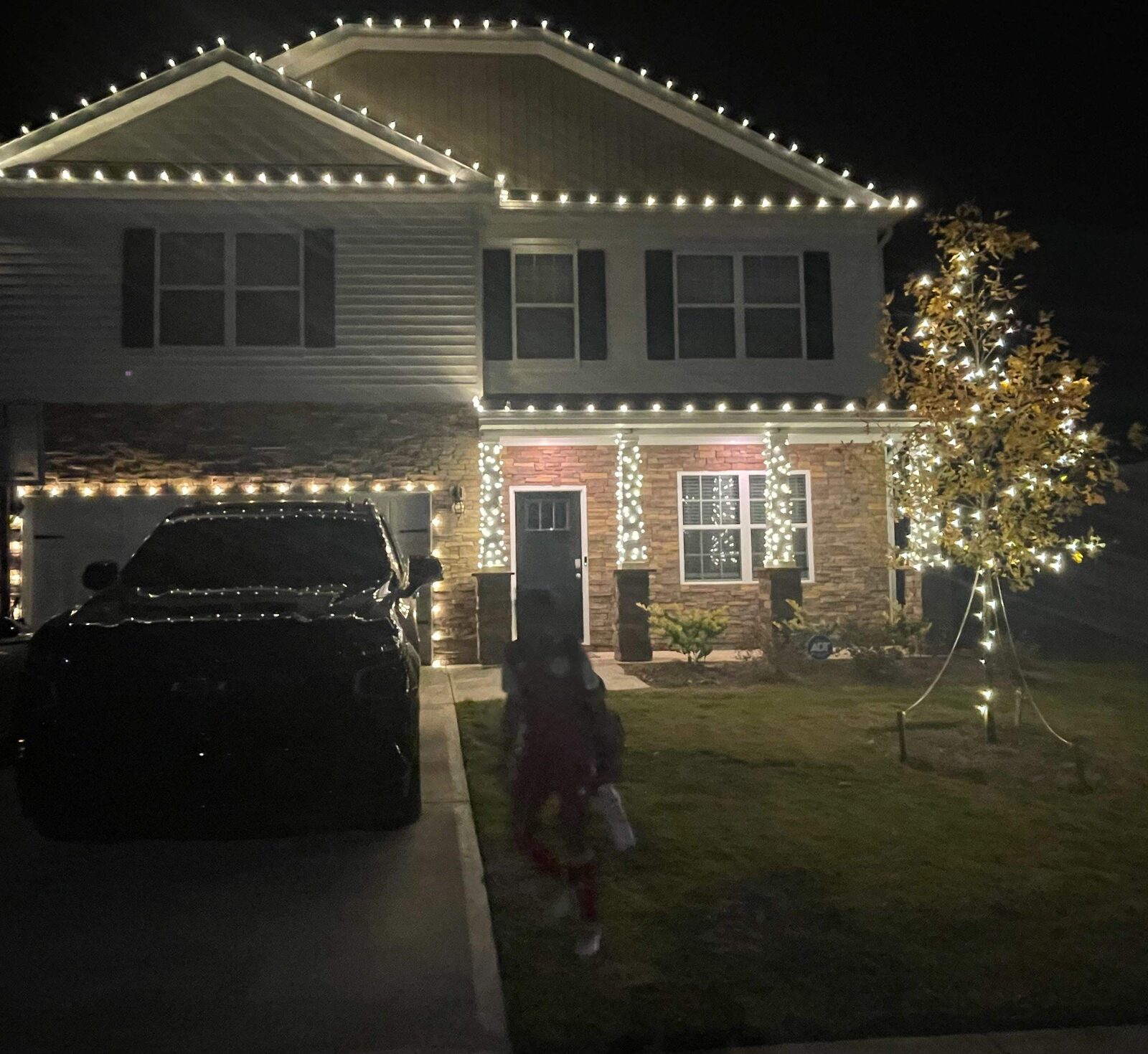 Home with Christmas roofline lights and a lit yard tree