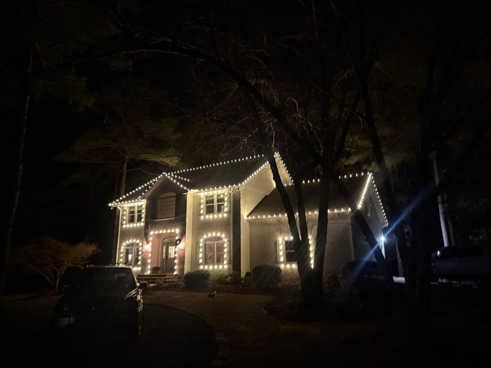 White brick home outlined in warm white Christmas lights
